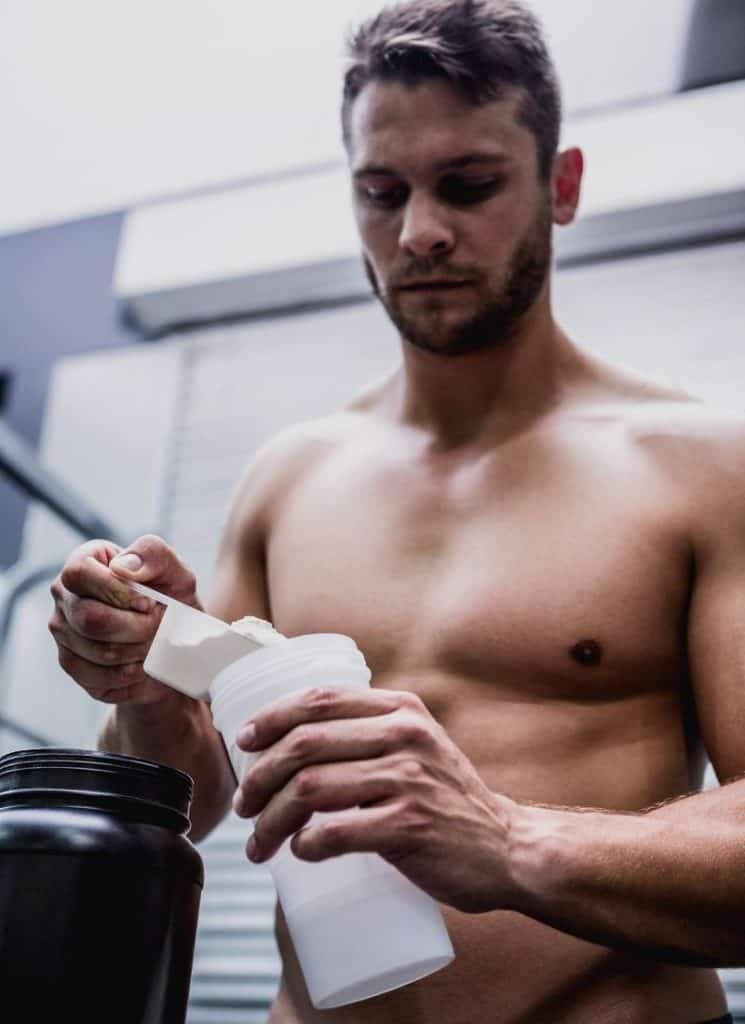 A man pouring powder in a tumbler.