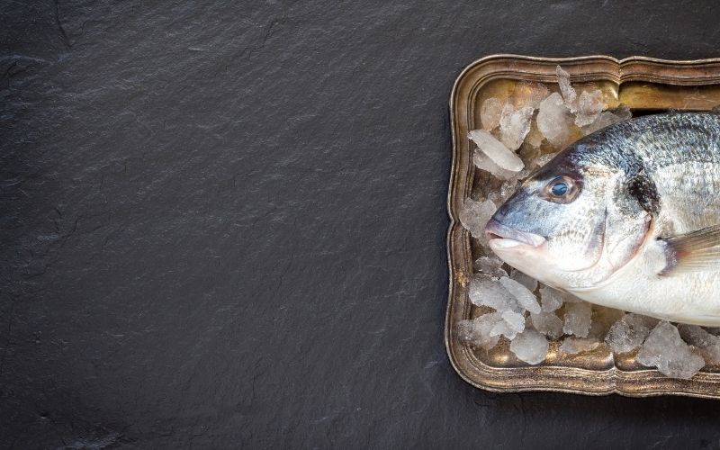 Raw fish on a tray on a grey surface.