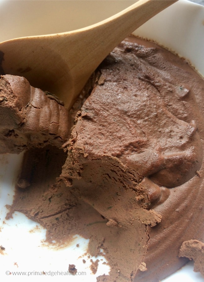 Keto chocolate pudding in a bowl with a wooden spoon.