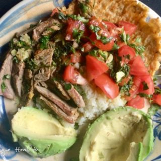 A plate with carne asada and rice, served alongside fresh avocado.