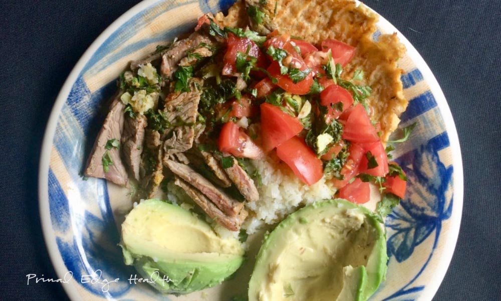 A plate with carne asada and rice, served alongside fresh avocado.