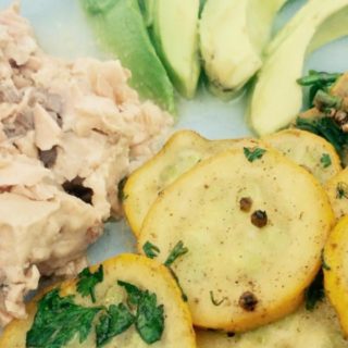 Salmon, avocado and slices of potatoes on a white surface.
