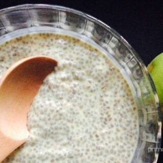 Chia pudding in a bowl with a wooden spoon next to limes.