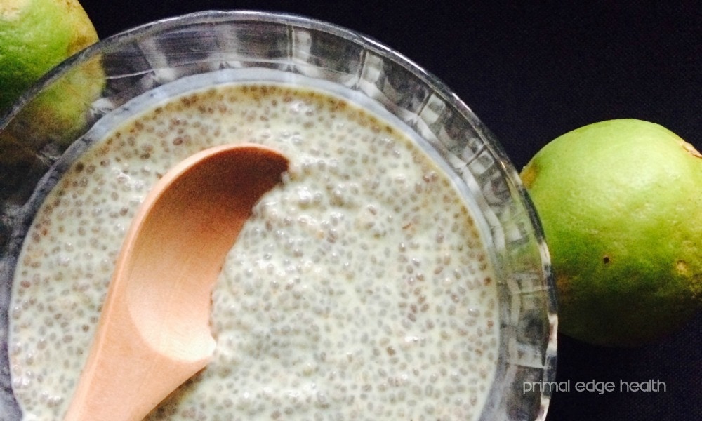 Chia pudding in a bowl with a wooden spoon next to limes.