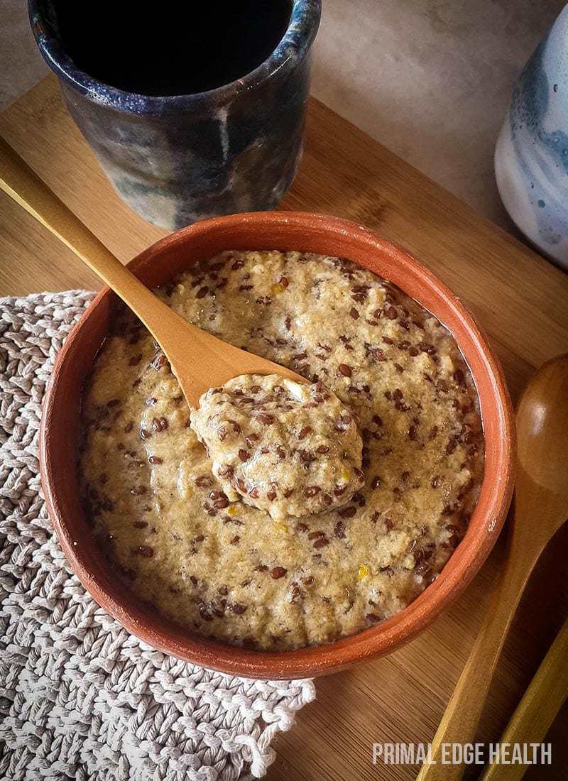 Hot keto cereal served in a brown bowl with a wooden spoon.