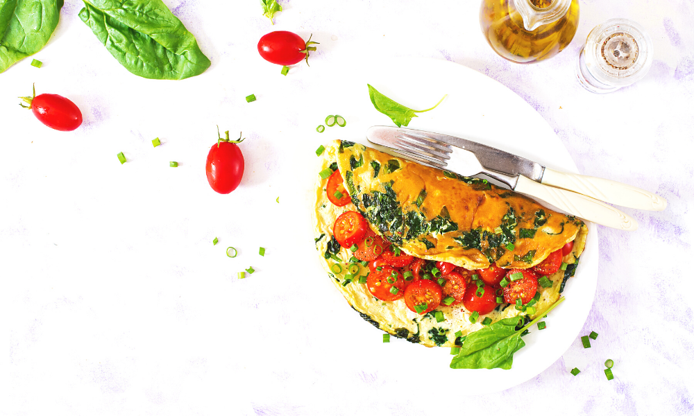 A keto omelette with tomatoes and spinach on a white plate.