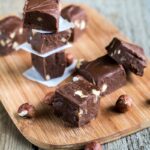 Pieces of Keto Nutella Fat Bombs on a wooden board on a wooden surface.