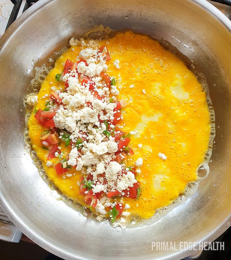 Egg being cooked in a pan with garnish.