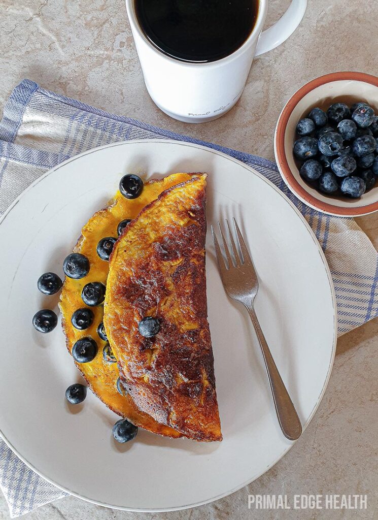 Sweet omelette on a plate with a side of blueberries.