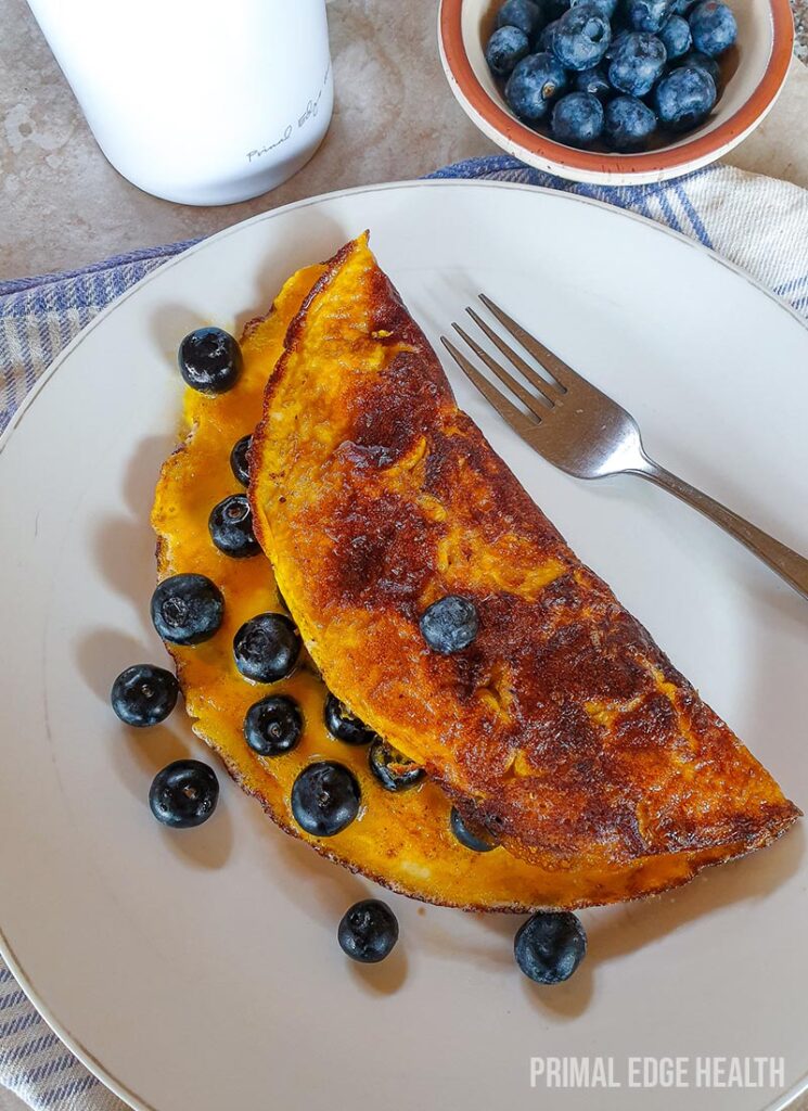 A plate of Sweet omelette with blueberries served with a fork.