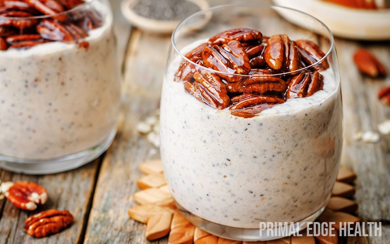 Two glasses of chai latte chia pudding on a wooden surface.