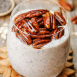 Chai latte chia pudding in a glass on a wooden surface.