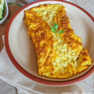 A plate of three cheese omelette with garnish on a white surface.