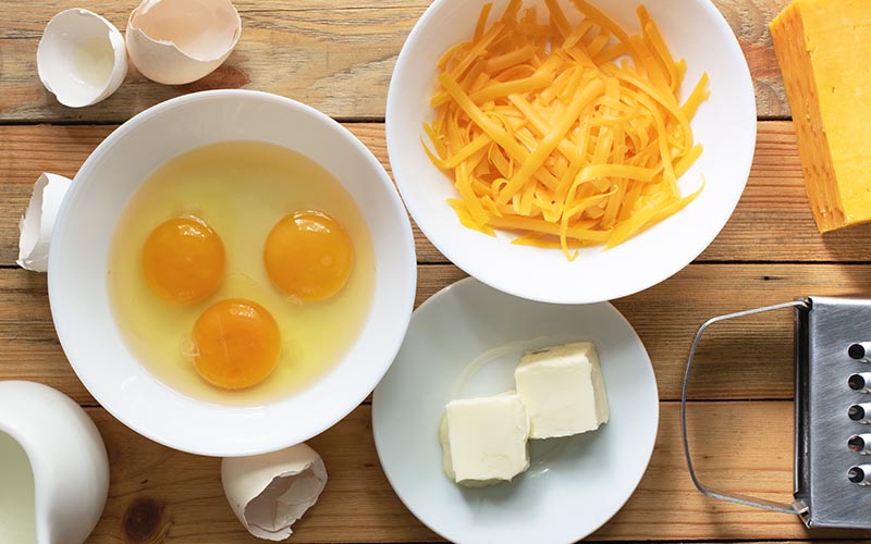 Ingredients of three cheese omeltte on a wooden surface.