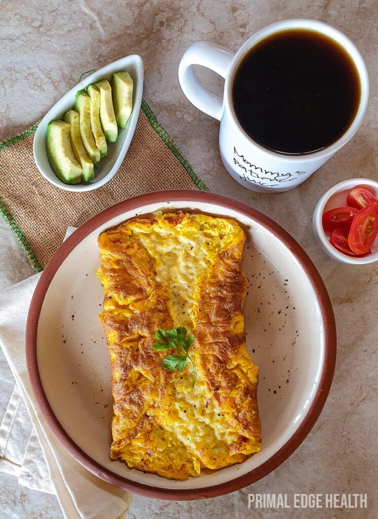 Three cheese omelette on a plate served with a cup of coffee.