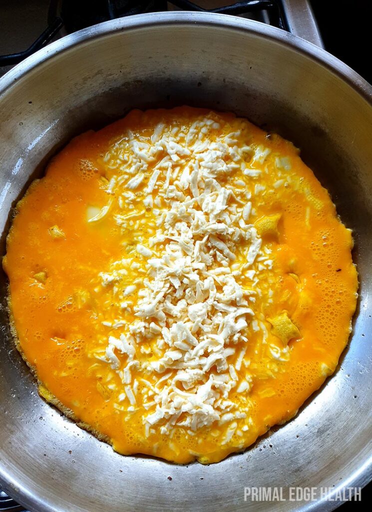Egg being cooked in a pan with cheese on top.