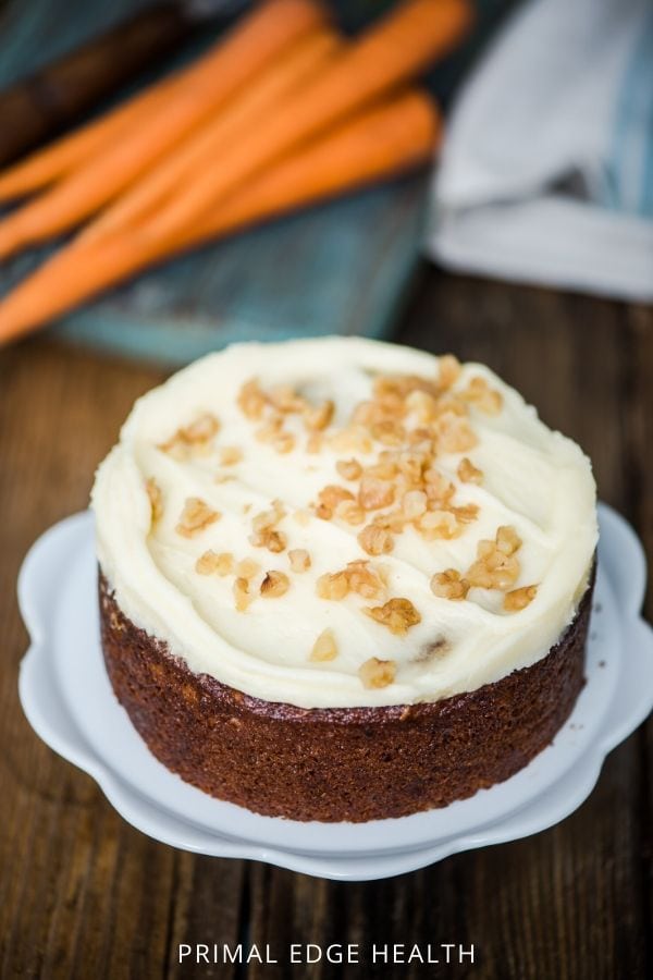 A whole carrot cake with cream cheese frosting and nuts.