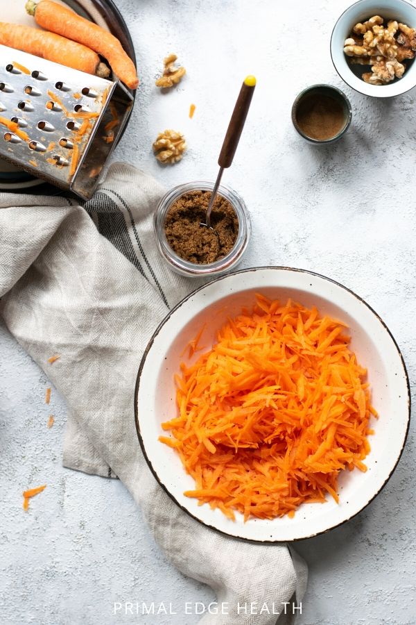 Simple ingredients for keto carrot cake on a white surface.