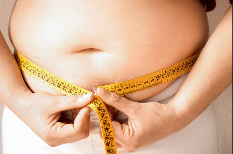A person measuring the waist area of her body.