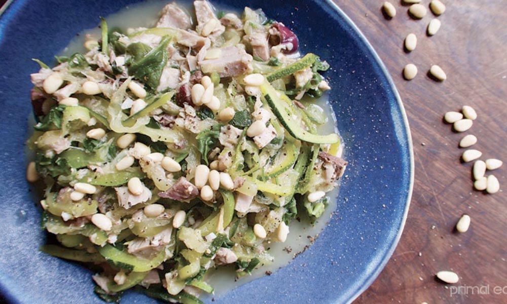 Zoodles with tuna and pine nuts on a blue plate.