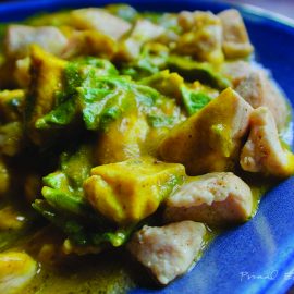 A keto curry dish on a blue plate with chicken and vegetables.