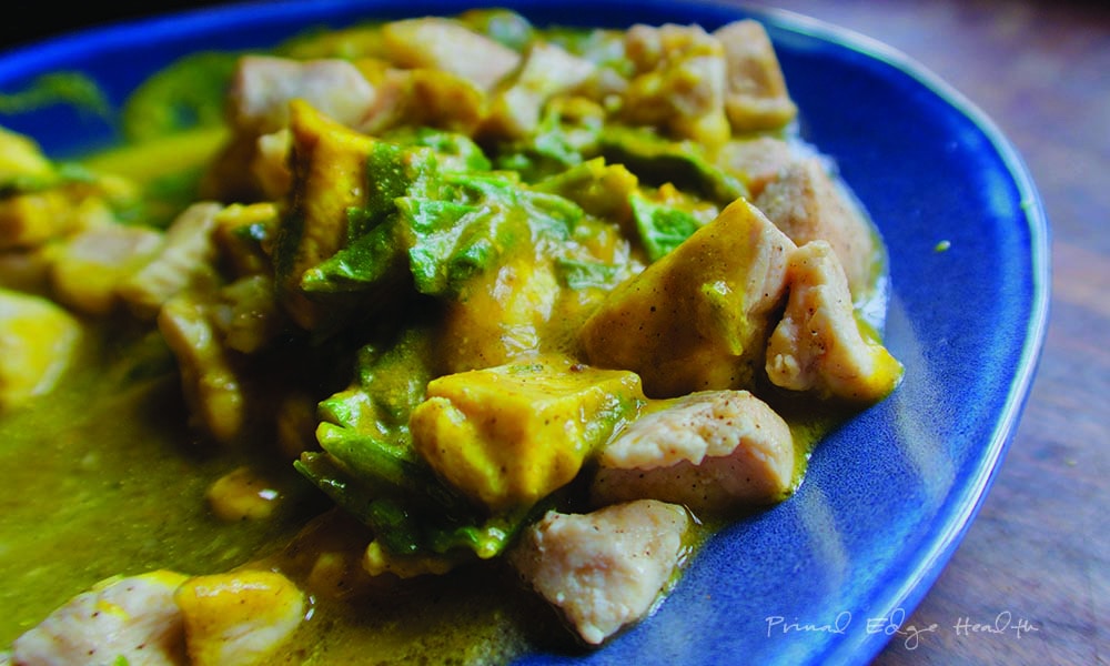 A keto curry dish on a blue plate with chicken and vegetables.