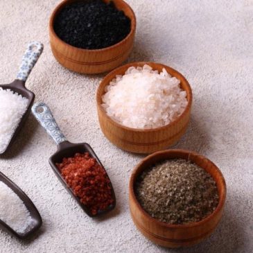 Various types of salt in bowls and scoops.