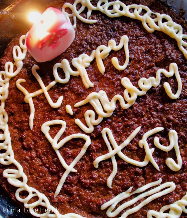 A dairy-free birthday cake with a candle on it, topped with keto icing.