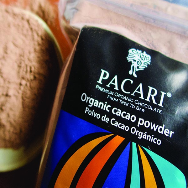 A bag of pacari organic cacao powder beside a bowl of organic cacao powder.