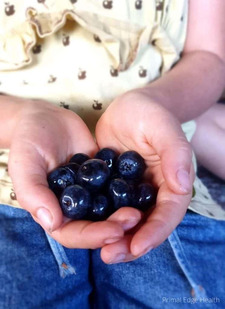 A woman holding a bunch of blueberries.
