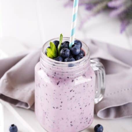 A glass of vegan keto smoothie recipe served with a blue and white straw.