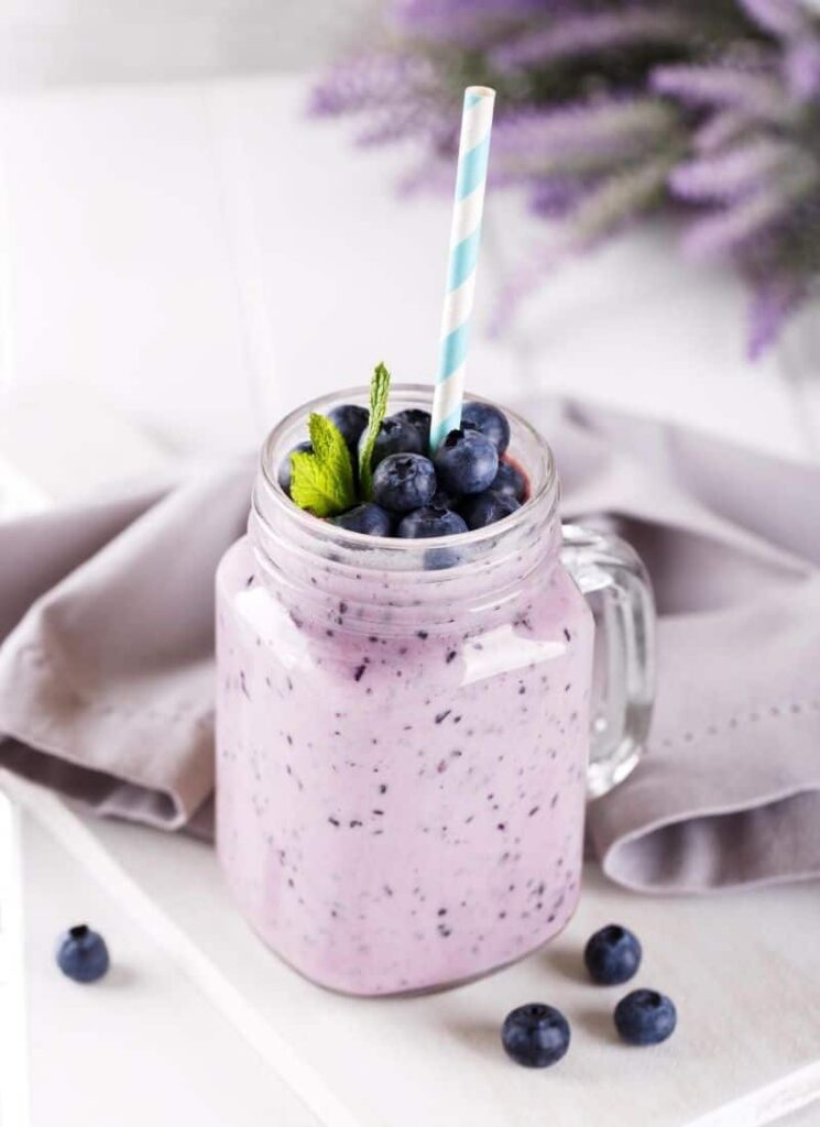 A glass of vegan keto smoothie recipe served with a blue and white straw.