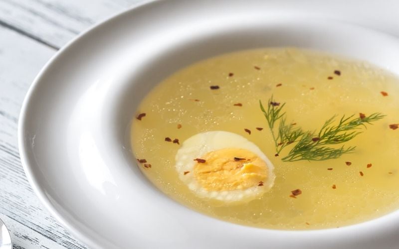 Yellow soup garnished with egg and herbs.