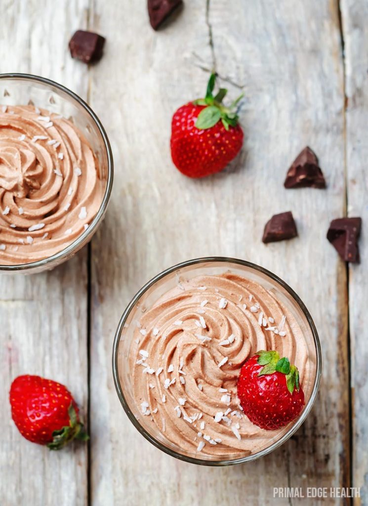 Two glasses keto chocolate mousse on a wooden surface.