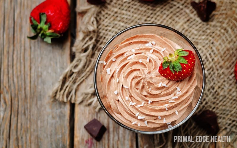 A glass of keto chocolate mousse garnished with strawberry.