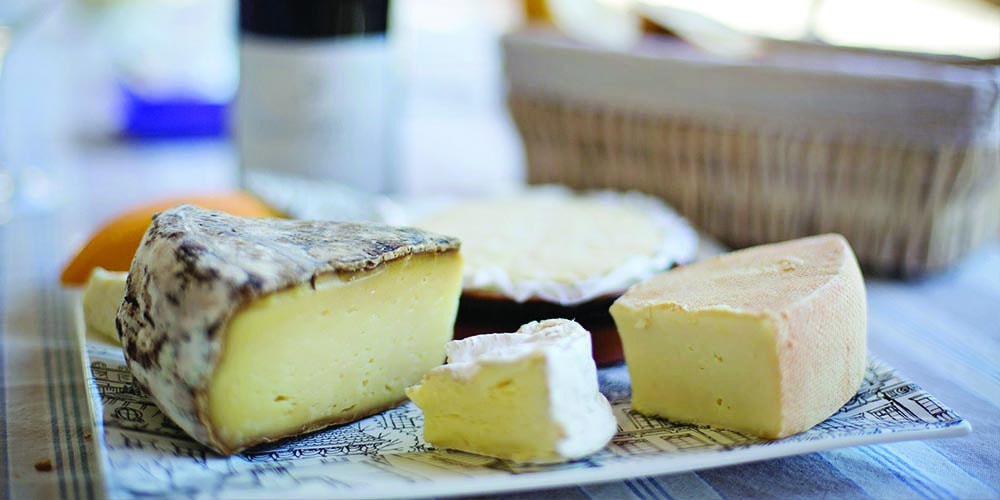 Slices of different kinds of cheese on a plate.