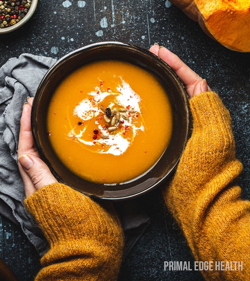 A person's hands holding a bowl of low-carb pumpkin soup.