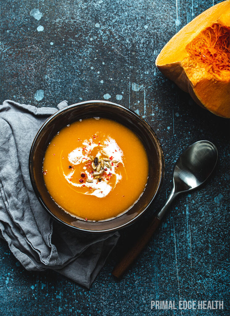 A bowl of low-carb pumpkin soup on a blue surface.