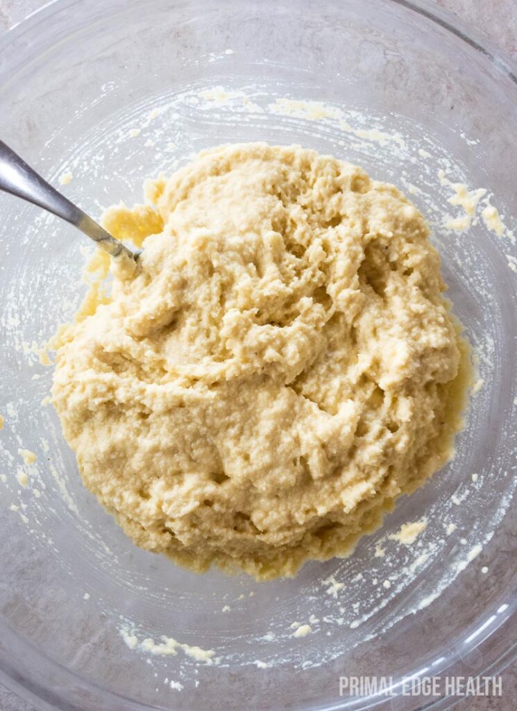 Drop biscuits batter being mixed in a glass bowl with a fork.