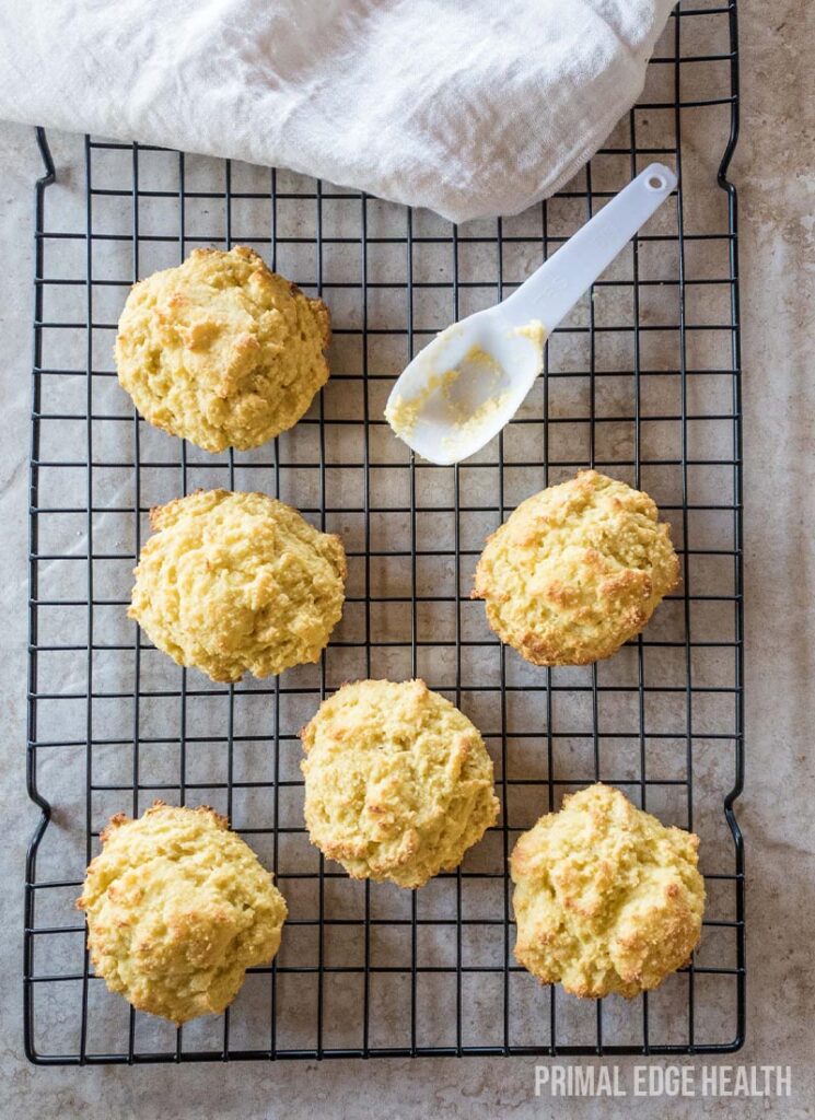 Drop biscuits on a wire rack with a white spatula.