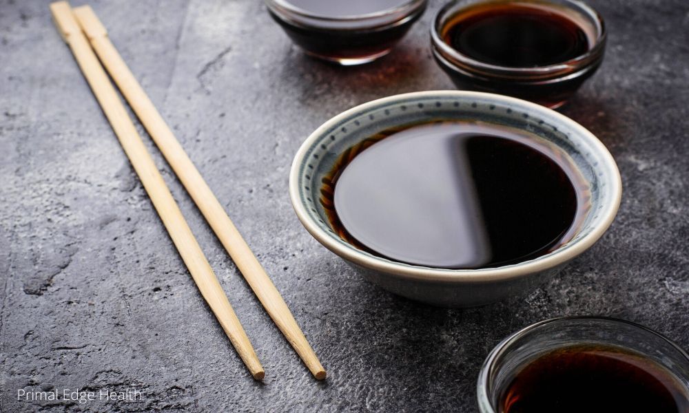 Small bowls of soy sauce with wooden chopsticks on dark background.