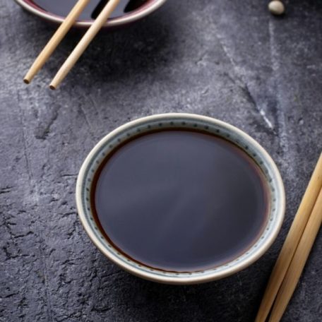 Two small bowls of keto friendly soy sauce on a grey surface.