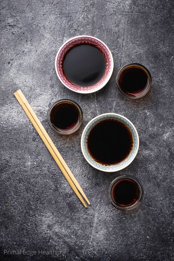 Soy sauce in various containers on a grey surface.