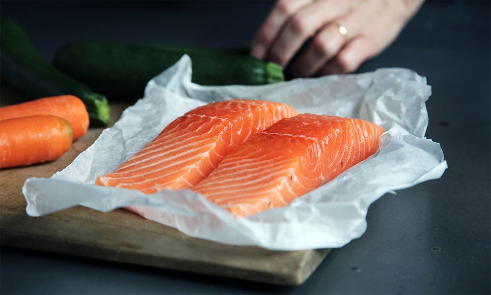 Two slices of salmon belly on a parchment paper.
