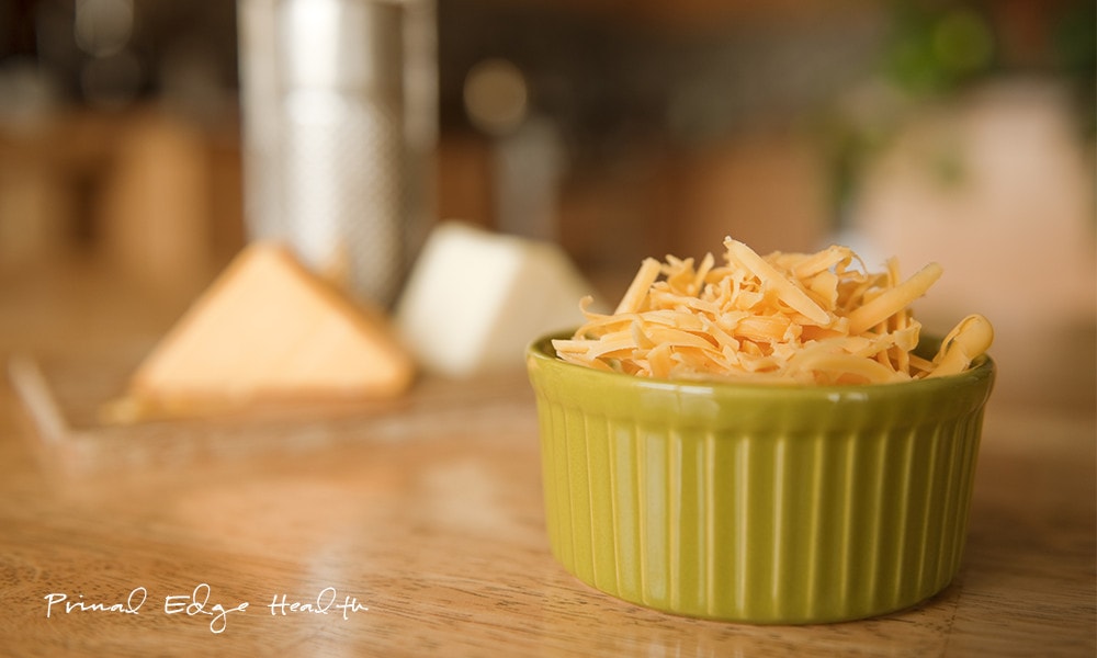 Grated cheddar cheese in green cup.