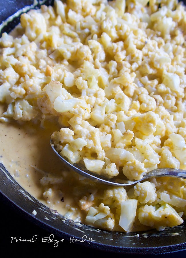 A bowl of cauliflower keto mac and cheese with a spoon in it.