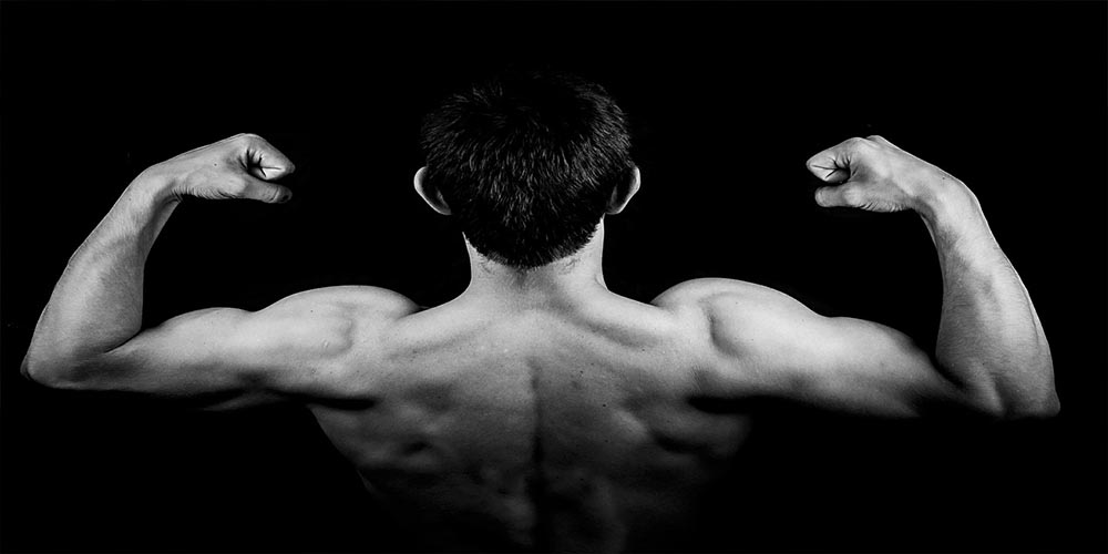 Back of a man who is flexing his upper body muscle.
