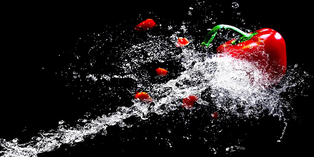 Water hitting a red bell pepper.