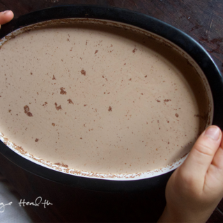 A child holding a dish full of no-bake eggnog cheesecake.