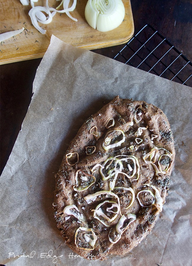 Low-carb focaccia bread on a parchment paper on top of a cooling rack.